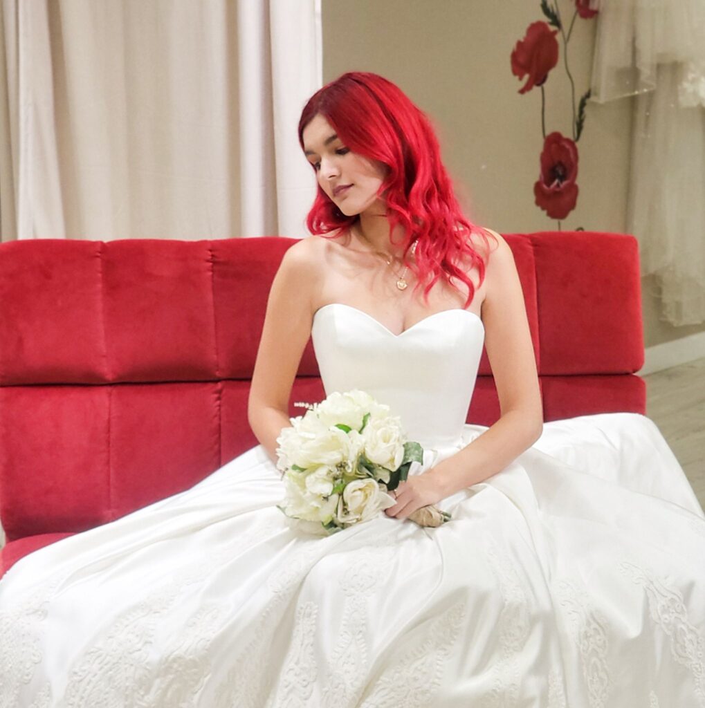 bride wearing satin ballgown wedding dress, sitting on couch