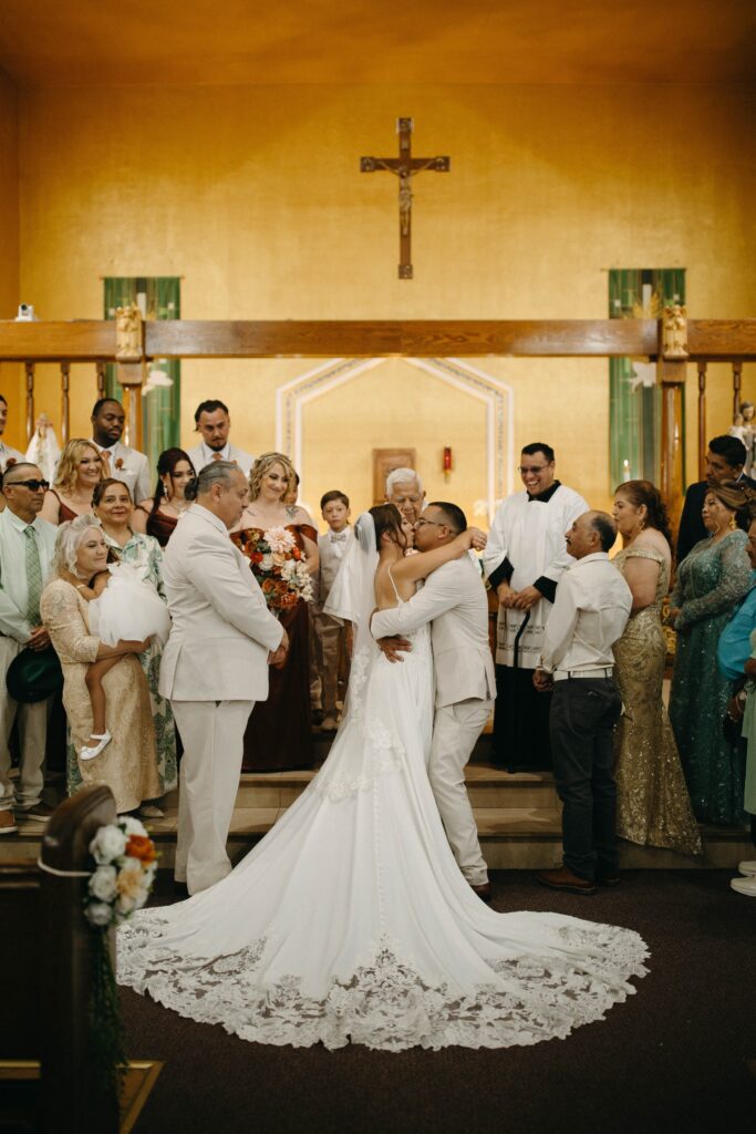 groom and bride wearing off the rack wedding dress kissing in church